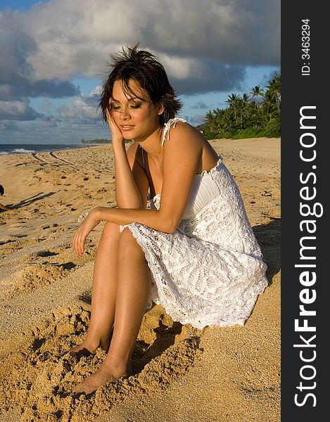 girl sitting on the beach in a white dress
