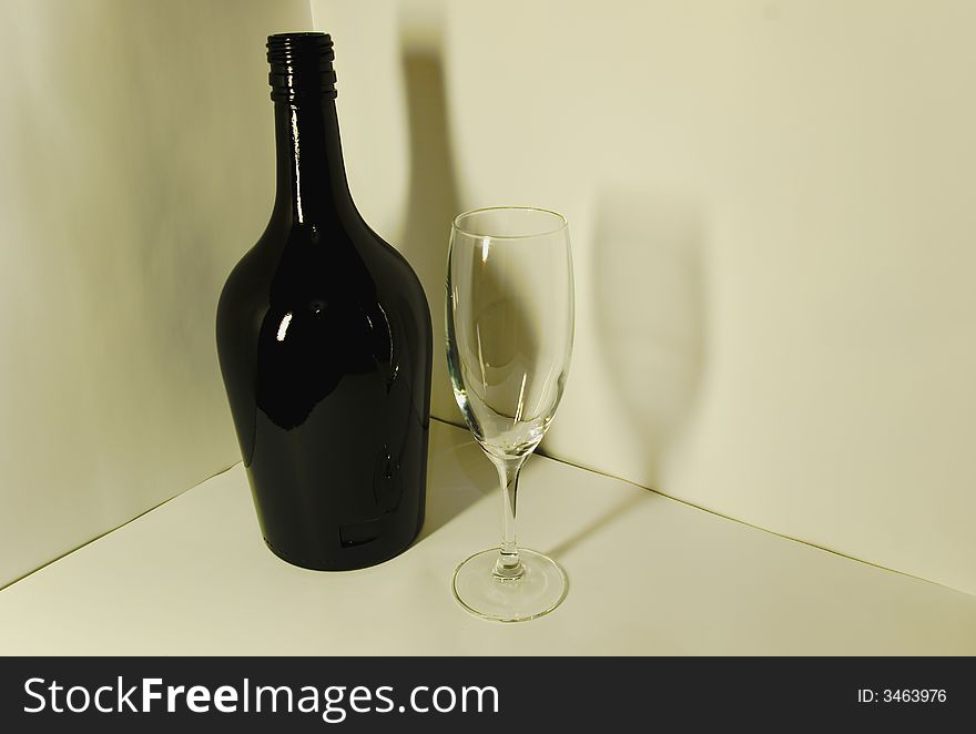 Photo of a black bottle and glass on a white background