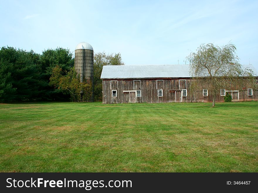 A Barn and silo with trees and grass