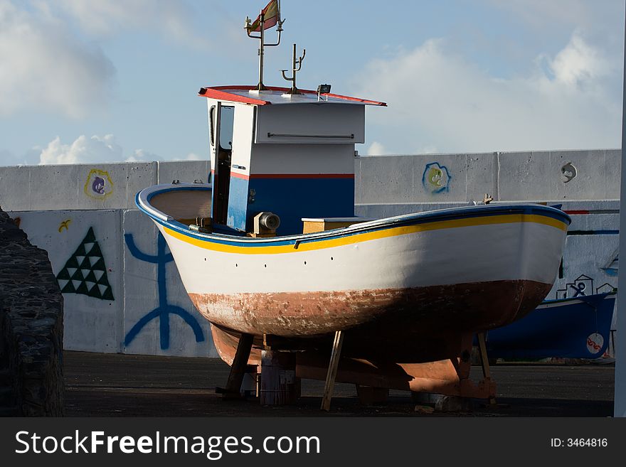 A fishing boat out of the water and up on blocks for maintenance. A fishing boat out of the water and up on blocks for maintenance