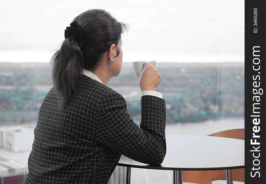 Business woman having a short coffee break in cafeteria, looking through window. Business woman having a short coffee break in cafeteria, looking through window