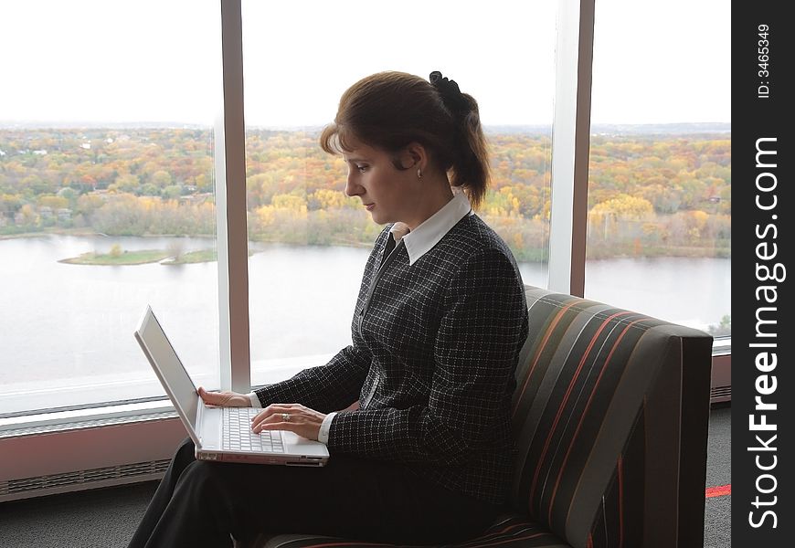 Business woman working on laptop in the hall of office building. Business woman working on laptop in the hall of office building