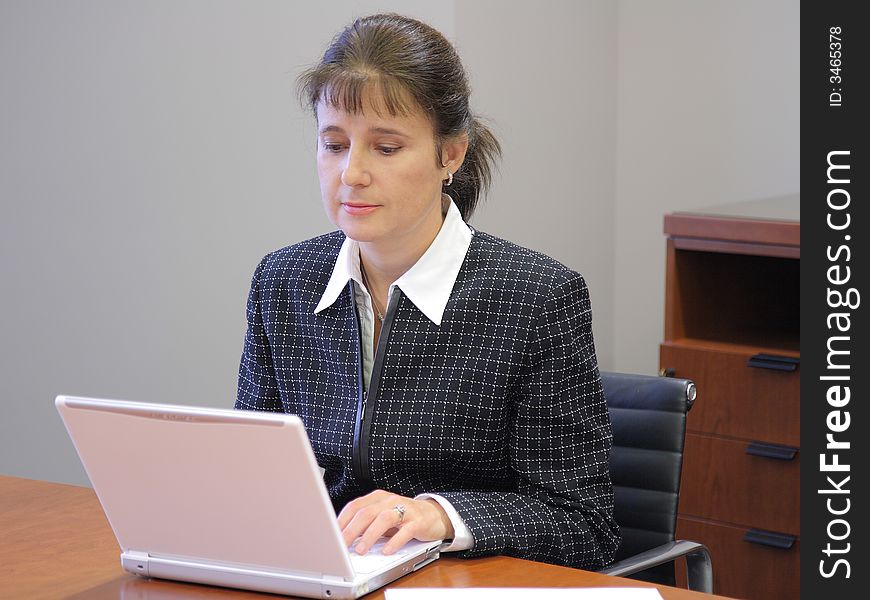 Business woman working with documents on a laptop in her office. Business woman working with documents on a laptop in her office