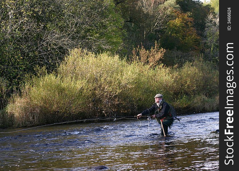 Fly Fisherman  casting line forward.  Fly Fisherman  casting line forward