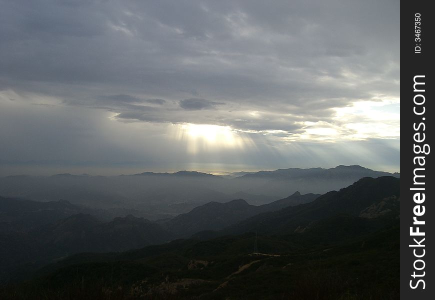 Sunlight Beaming Through Clouds Onto Many Mountains