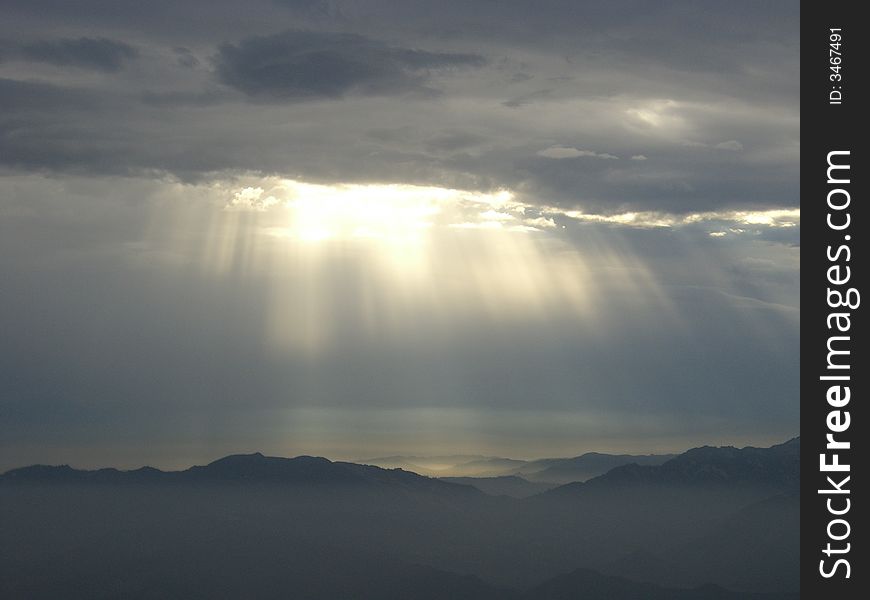 Sunlight Beaming Through Clouds Onto Many Mountains