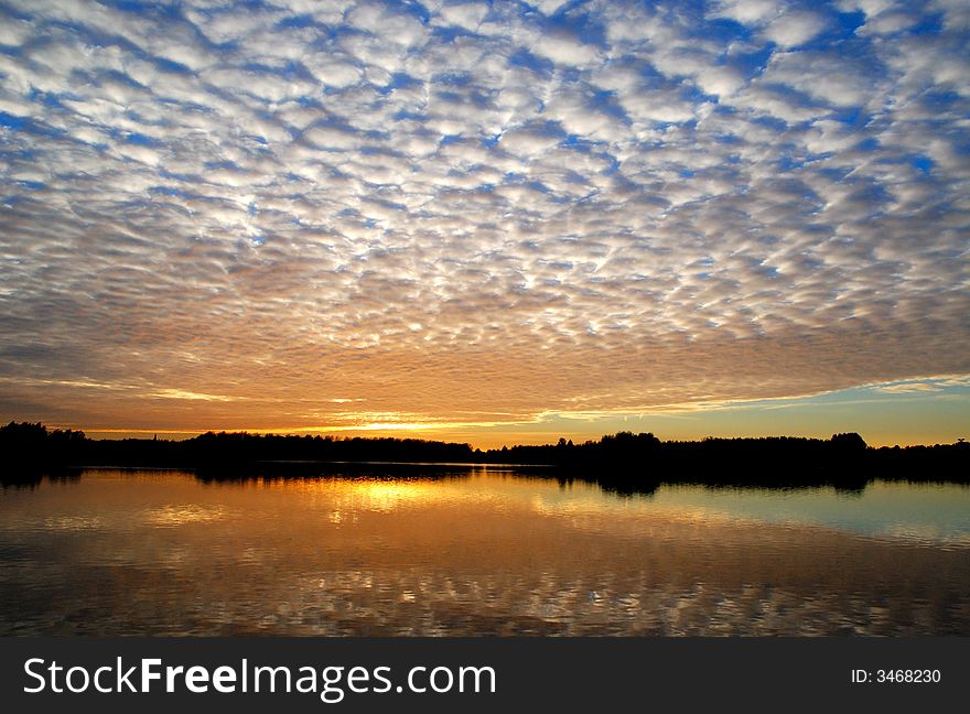 Puffy clouds over a small lake with sunset. Puffy clouds over a small lake with sunset