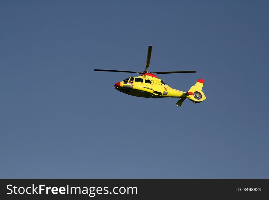 Side view of a yellow rescue helicopter in high flight. Side view of a yellow rescue helicopter in high flight.