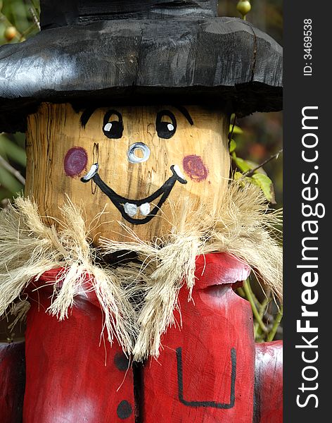 A hand carved wooden scarecrow used in a beautiful seasonal display.
