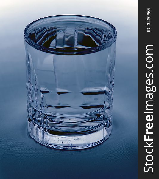 A glass filled with water on a blue/white background. A glass filled with water on a blue/white background