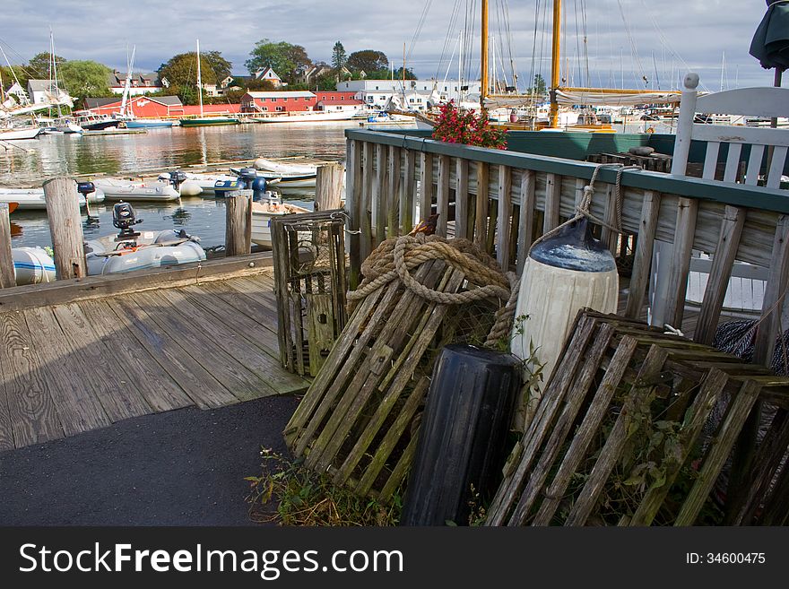 Fishing harbor in Maine, from the perspective of standing on the dock with lobster traps in the foreground.