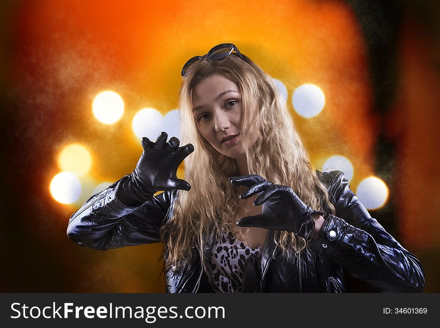 Beautiful girl in black gloves on the background of orange lights
