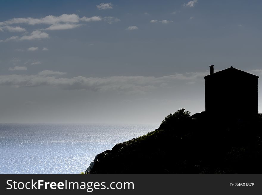 Silhouette of a small house with the background of the sea.