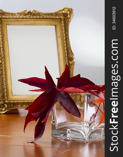 Autumn leaves in a glass vase and a photo frame in retro style. Autumn leaves in a glass vase and a photo frame in retro style