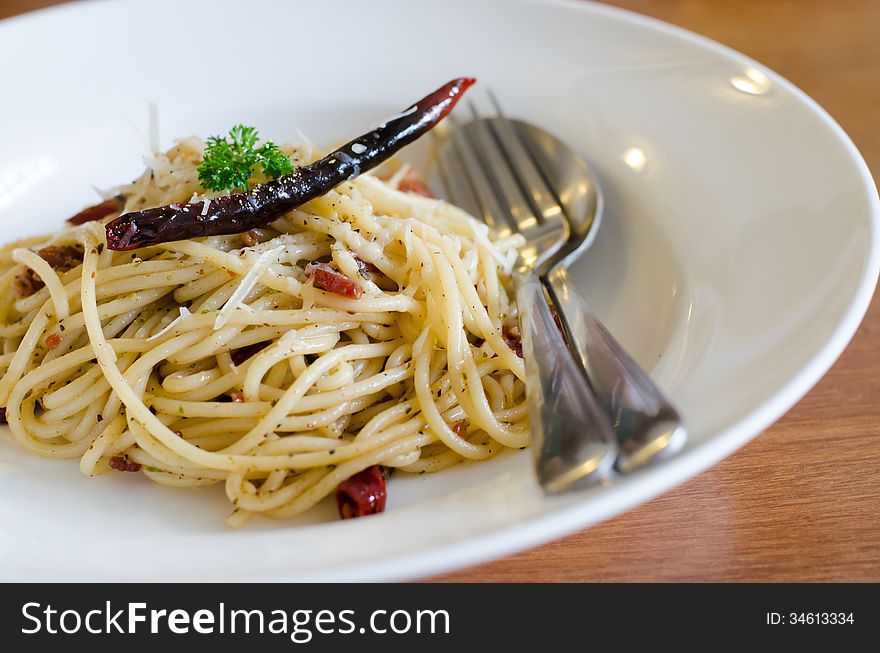 Spaghetti with ham , bacon, chilli and basil in white plate