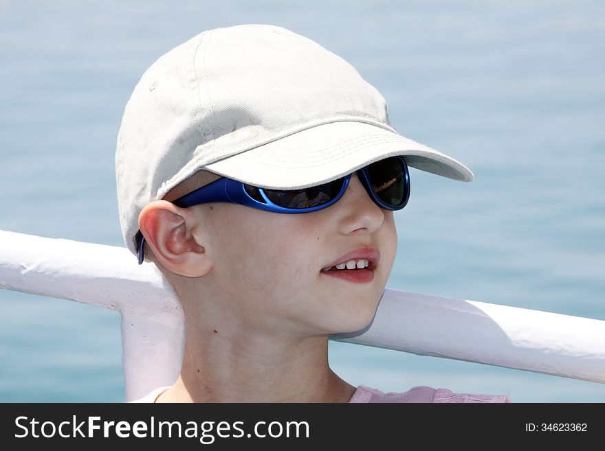 Child with cancer wearing a cap and sunglasses to shade herself from the sun's rays. Child with cancer wearing a cap and sunglasses to shade herself from the sun's rays