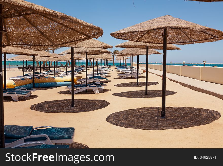 Deserted beach, sunshades, chaise lounges
