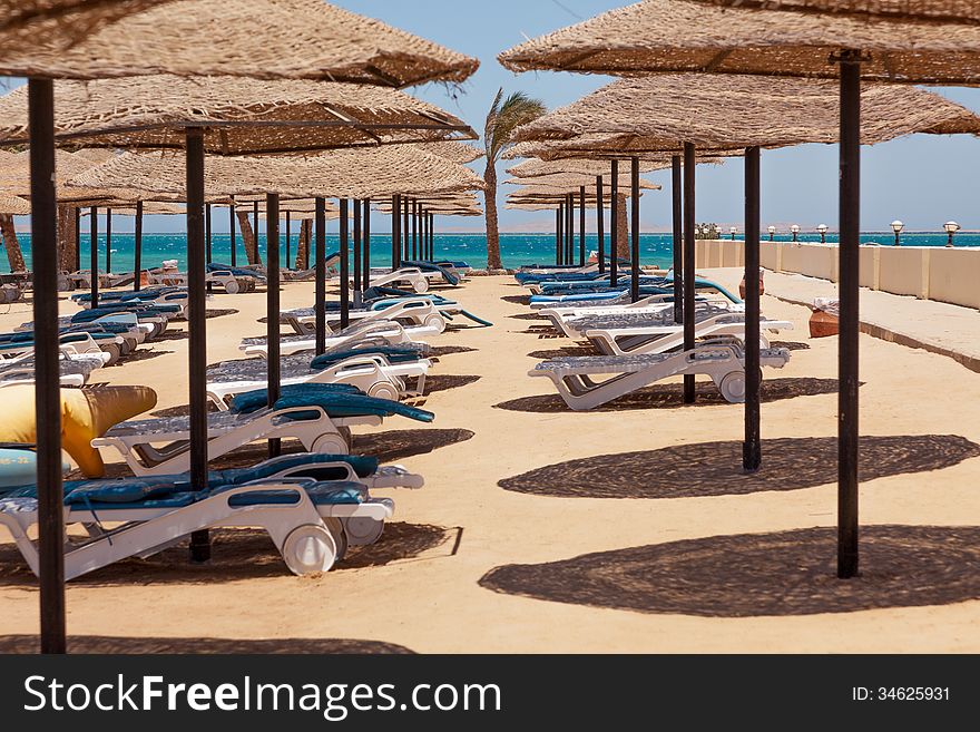 Deserted beach, sunshades, chaise lounges