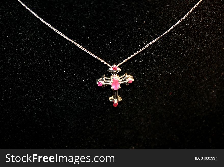 Ruby cross necklace on a black background