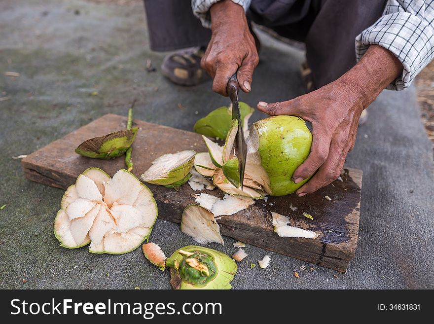 Man peeling coconut fruit with knife