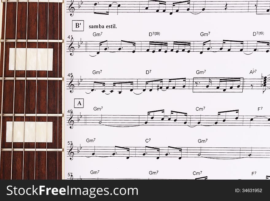 Guitar Neck Laying Across Sheet Music