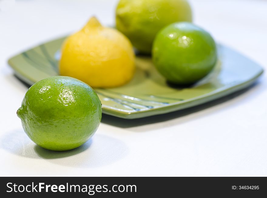 Lemons and limes on a green plate, blurred background. From the series Healthy Eating