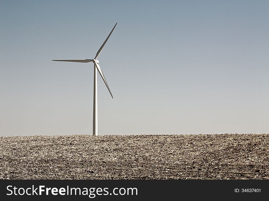 Single wind turbine in a field against a clear blue sky. Single wind turbine in a field against a clear blue sky.