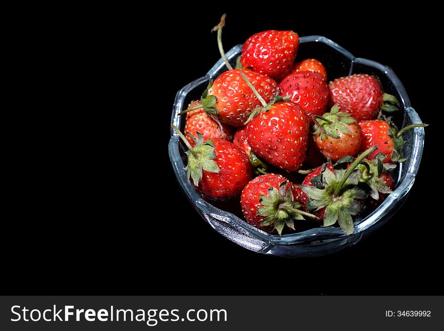 A bowl of strawberry, over black background