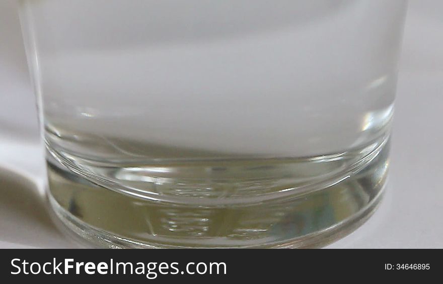 Clip of an effervescent pill being dropped in a glass of water.