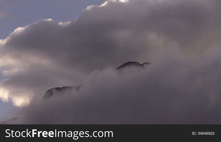 Dark clouds floating over a mountain peak, resembling smoke. Dark clouds floating over a mountain peak, resembling smoke.