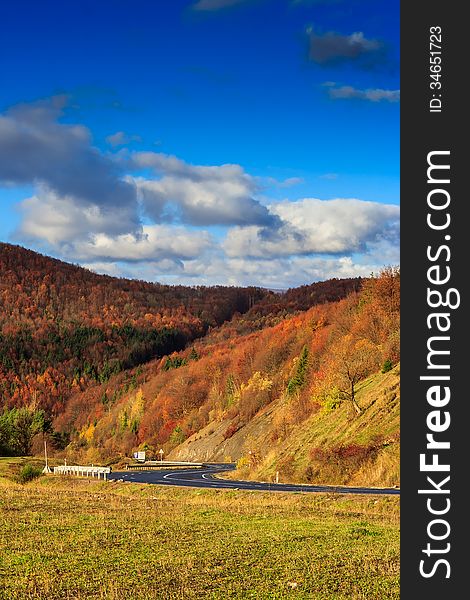 Autumn mountain landscape. S-curve road in the morning at the foot of the mountain. on the mountain forest with red and yellow leaves. Autumn mountain landscape. S-curve road in the morning at the foot of the mountain. on the mountain forest with red and yellow leaves