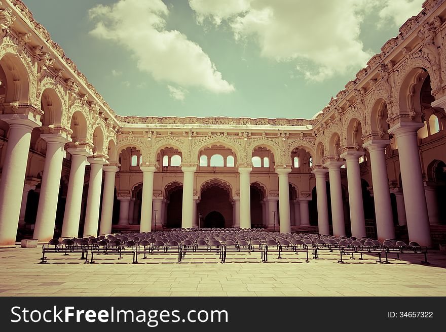 Rows of chairs at outdoors concert hall with ancient columns under cloudy sky. Thirumalai Nayak Palace. India, Madurai. Vintage style image