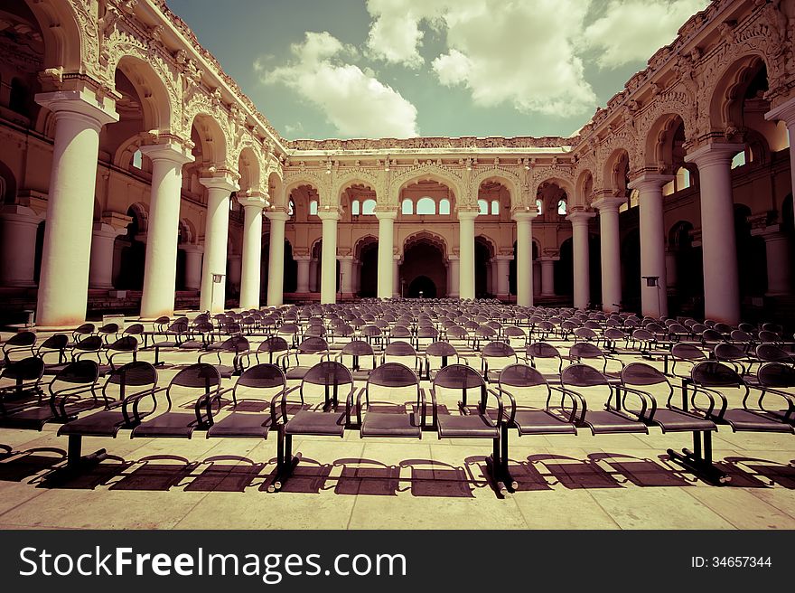 Rows of chairs at outdoors concert hall with ancient columns under cloudy sky. Thirumalai Nayak Palace. India, Madurai. Vintage style image