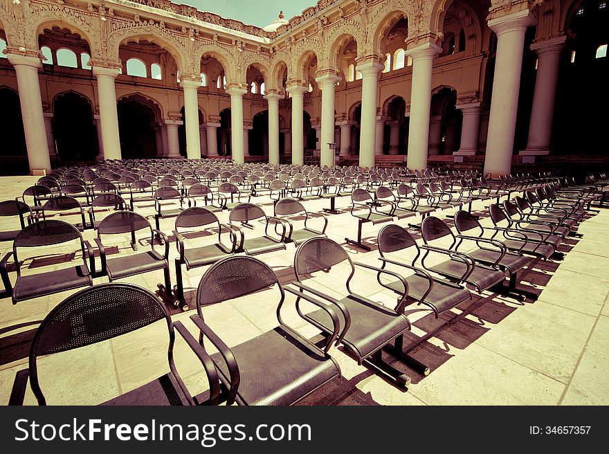Rows of chairs at outdoors concert hall with ancient columns under cloudy sky. Thirumalai Nayak Palace. India, Madurai. Vintage style image