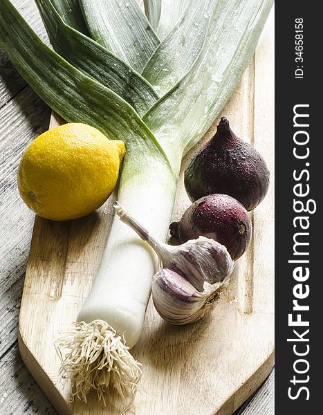 Fresh onion, garlic and lemon on a wooden cutting board.