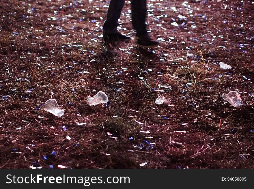 Beer cups and debrees with feet after concert, garbage, confetti, grass, broken beer glass, moving steps, moving feet, walking