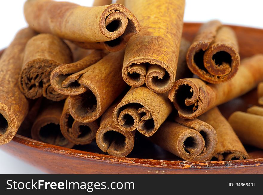 Flavored Cinnamon Sticks on Brown Plate closeup on white background