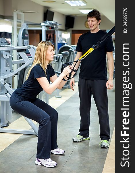 Woman in the fitness gym working out with personal trainer coach. Woman in the fitness gym working out with personal trainer coach