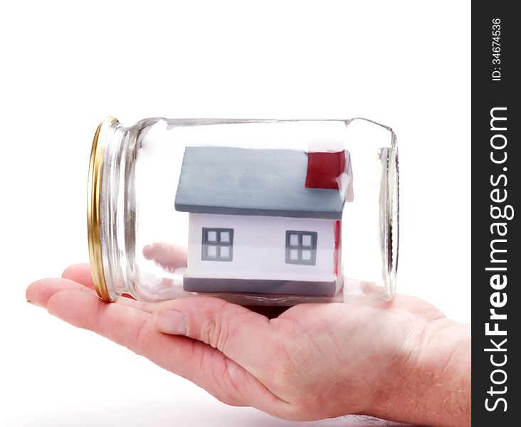 Property insurance. metaphor. mans hand carefully holding toy house model in a closed glass jar