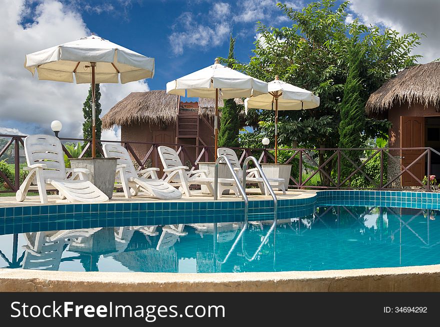 Swimming pool with sunbeds surrounded by tropical plants