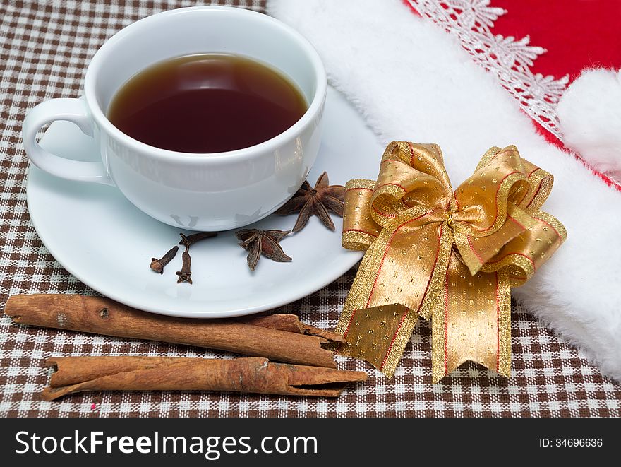 Cup of tea with cinnamon pipes, golden ribbon and Santa's hat