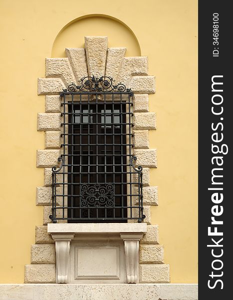 Window in Verona with features and forged metal bars on the wall yellow house