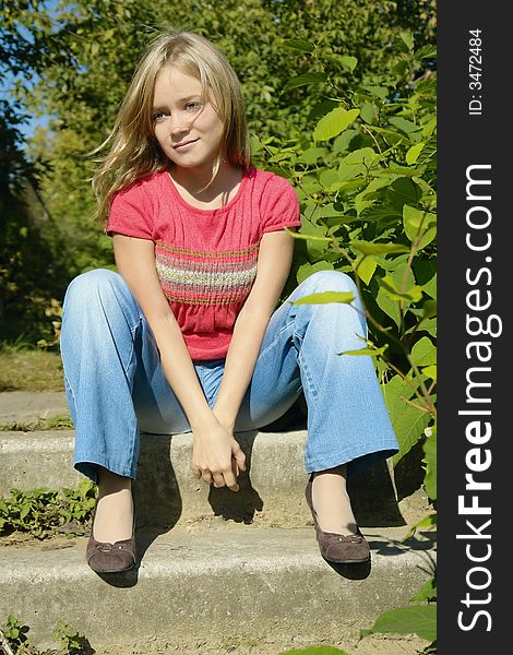 Blond girl sitting on footsteps in the park