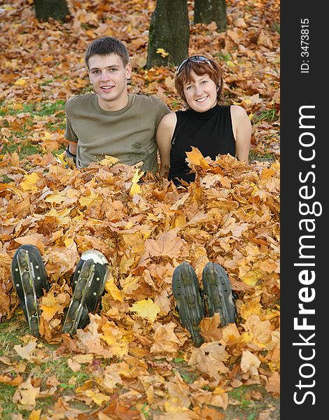 Young roller couple sit in yellow leaves