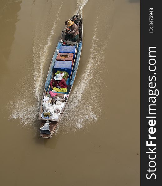 Classic wooden boat at speed on a canal in Thailand, on its way to a floating market. Classic wooden boat at speed on a canal in Thailand, on its way to a floating market.