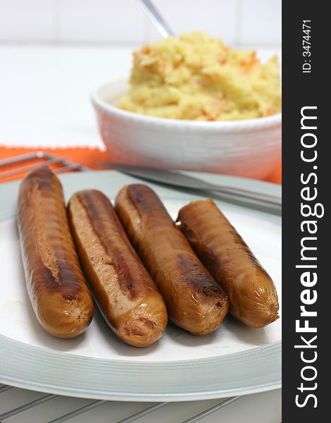 Four large pan grilled frankfurters with mash in the background. Four large pan grilled frankfurters with mash in the background