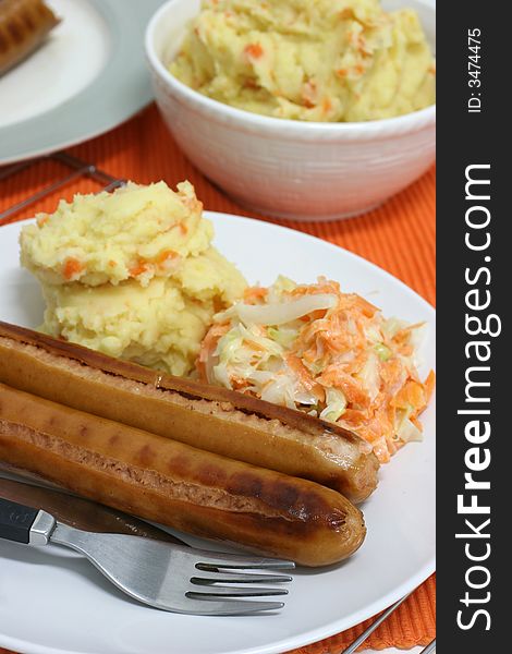 Large frankfurters with carrot and cabbage coleslaw and mash for dinner. Large frankfurters with carrot and cabbage coleslaw and mash for dinner