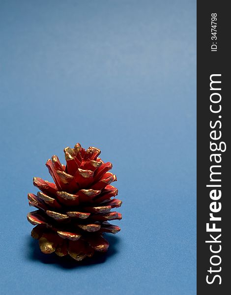 Red christmas pine cone isolated on blue background. Red christmas pine cone isolated on blue background