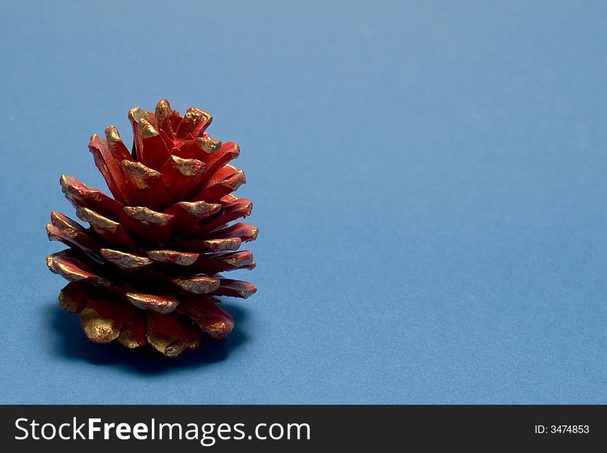 Red christmas pine cone on blue background. Red christmas pine cone on blue background
