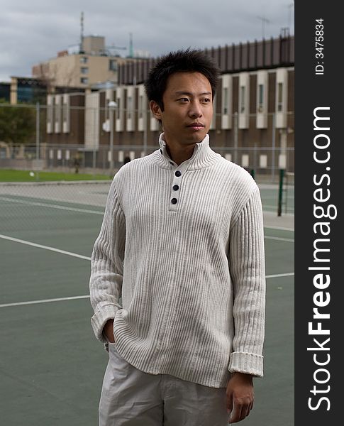 A boy standing in tennis court wearing sports clothing. A boy standing in tennis court wearing sports clothing